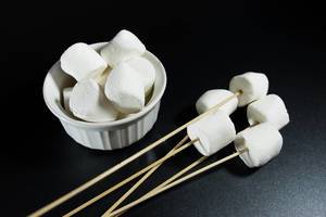 Marshmallows in a bowl and wooden sticks