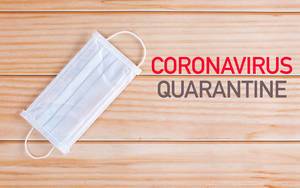 Medical mask with Coronavirus Quarantine text on wooden background