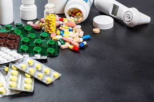 Medikamente, Tabletten und Thermometer auf schwarzem Hintergrund