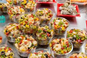 Mediterraner Salat mit Shrimps, Oliven und frischem Gemüse, wird als Fertigessen in der Mercat de la Boqueria Markthalle in Barcelona (Spanien) verkauft