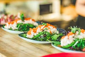 Meeresfrüchtesalat auf geschwungenen Tellern, mit Lachscreme und Kaviar