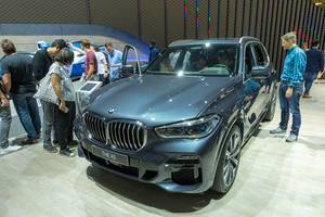 Menschen betrachten den Plugin-Hybrid BMW x5 xDrive45e mit Vierzylinder-Benziner und Elektromotor