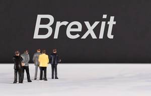Menschenfiguren stehen vor einer schwarzen Wand mit  "Brexit" als Text