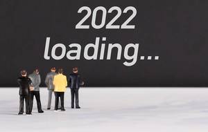 Menschenfiguren stehen vor einer Wand mit  "2022 loading" als Text