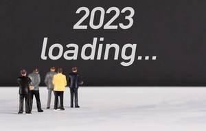 Menschenfiguren stehen vor einer Wand mit  "2023 loading" als Text
