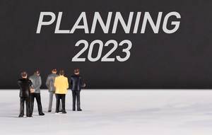Menschenfiguren stehen vor einer Wand mit  "Planning 2023" als Text