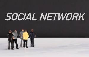 Menschenfiguren stehen vor einer Wand mit  "Social network" als Text