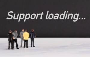 Menschenfiguren stehen vor einer Wand mit  "Support loading" als Text