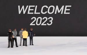 Menschenfiguren stehen vor einer Wand mit  "Welcome 2023" als Text