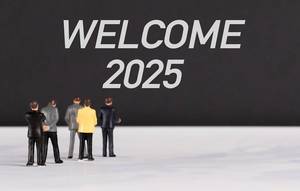 Menschenfiguren stehen vor einer Wand mit  "Welcome 2025" als Text