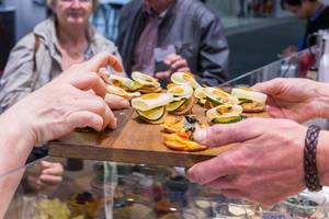Messekoch überreicht Fingerfood auf einem Holzbrettchen auf der IFA