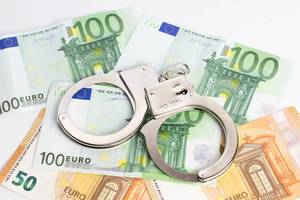 Metallic police handcuffs on euro banknotes