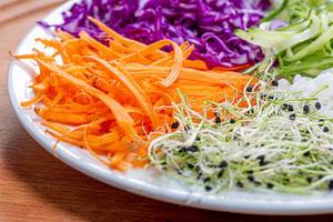 Micro-greens onions, carrots, cucumber, purple cabbage and rice on a white plate