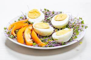 Mikrogreens / Superfood: Kohl mit gekochten, halbierten Eiern und orange Paprikastreifen