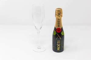 Mini-Flasche von Moët & Chandon Impérial mit einem leeren Sektglas: die Miniaturversion einer wahren Champagner-Ikone