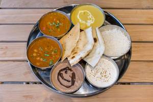 Mittagessen in einem indischen Restaurant, Schälchen mit Curry werden mit Reis und Fladenbrot serviert