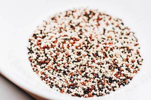 Mixed quinoa seeds in white bowl. Close up.