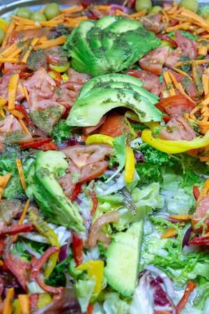 Mixed salad with tomatoes, colorful peppers and avocado on top
