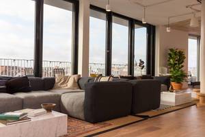 Modern eingerichtete Lounge mit Sofawecke und großer Fensterfront der gemeinschaftlichen Arbeitsraumfläche von WeWork in Köln