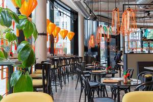 Modernes Interieur in dem Kölner coa Wok & Bowl Restaurant mit orangen Lampen, gelben Stühlen und grünen Pflanzen