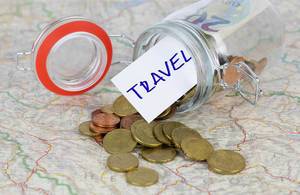 Money and a Travel Sign falling out of an open glass container laying on a map