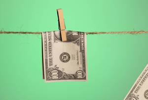 Money with wooden clothespin on clothes line with green background