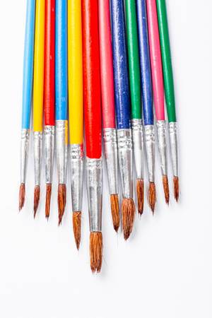 Multi-colored paint brushes on white background