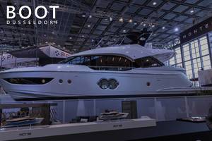 Multi-storey luxury yacht presented at a German boat show, next to picture title "Boot Düsseldorf"