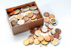 Münzen in einer kleinen Schachtel vor weißem Hintergrund