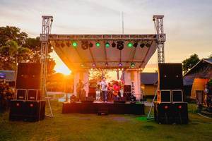 Musikband spielt auf einer kleinen Bühne ein Konzert, mit dem Sonnenuntergang im Hintergrund, im Camp Zion