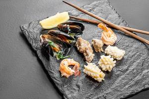 Mussels, shrimp, squid and fish on a black stone background