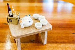 Nahaufnahme eines Miniatur-Porzellansets und kleinem Picknickkorb für ein Puppenhaus