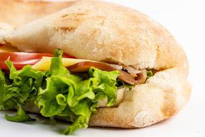 Nahaufnahme eines Sandwich mit grünem Salat, Tomaten, Schinken und Käsescheiben