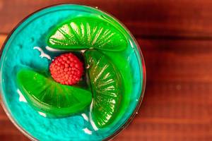 Nahaufnahme eines Wackelpudding Nachtisches mit grünem Weingummi und Himbeerkern in einem Glas