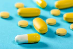 Nahaufnahme gelbe Pillen, Tabletten und Kapseln auf blauem Hintergrund