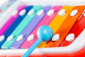Nahaufnahme hellblauer Spielstab auf Spielzeug-Xylophon in Regenbogenfarben
