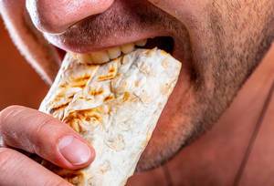 Nahaufnahme Mann mit Dreitagebart beißt genüsslich in Shawarma – Konzept von Fast-Food
