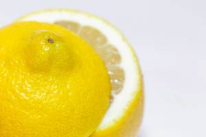 Nahaufnahme reife Zitrone mit frisch aufgeschnittenem Ende vor weißem Hintergrund