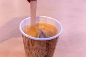Nahaufnahme umweltschonender Holzlöffel rührt Kaffee in recyclebarem Becher um