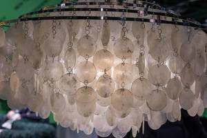 Nahaufnahme verspielte Lampe mit Ketten aus dünnen runden Glasplatten an mehreren Metallringen