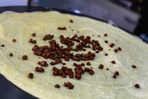 Nahaufnahme von bereits leicht geschmolzenen Schokoladechips auf frischer Crêpe