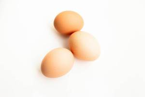 Nahaufnahme von drei Eiern mit brauner Eierschale freigestellt vor weiß