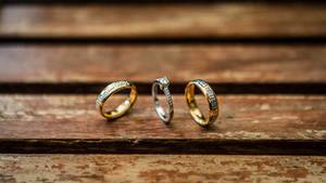 Nahaufnahme von Eheringen und Verlobungsring auf Tisch aus Holzlatten
