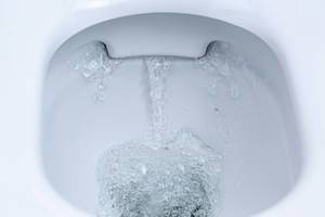 Nahaufnahme von einer spülenden Toilette im Badezimmer mit wirbelndes Wasser