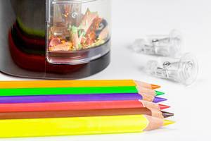 Nahaufnahme von farbigen Buntstiften mit elektrischem Anspitzer im Hintergrund