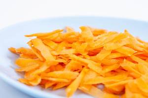 Nahaufnahme von frisch geraffelten Karotten auf weißem Teller