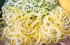 Nahaufnahme von in dünne Streifen geschnittener, gelber und grüner Zucchini