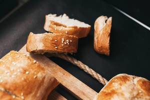 Nahaufnahme von in Scheiben geschnittenem, hausgemachtem französischem Brot mit Sesam vor dunklem Hintergrund