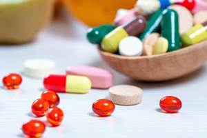 Nahaufnahme von Medikamenten, Pillen, Kapseln und Tabletten in einer Holzschale auf dem Tisch