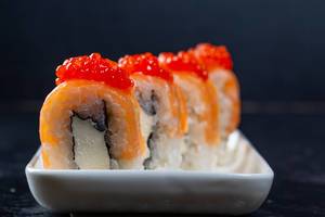 Nahaufnahme von Philadelphia Sushi Rollen mit Lachs, Käse und rotem Kaviar auf weißem Teller